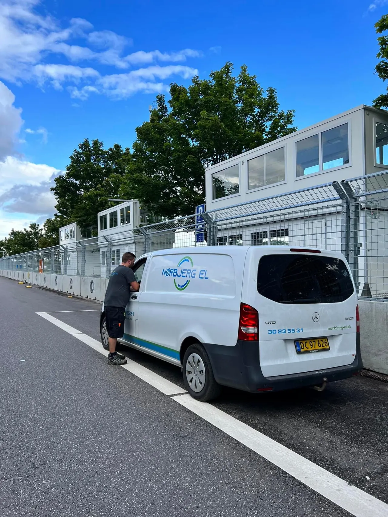 Nørbjerg El-varevogn parkeret langs hegnet ved en racerbane