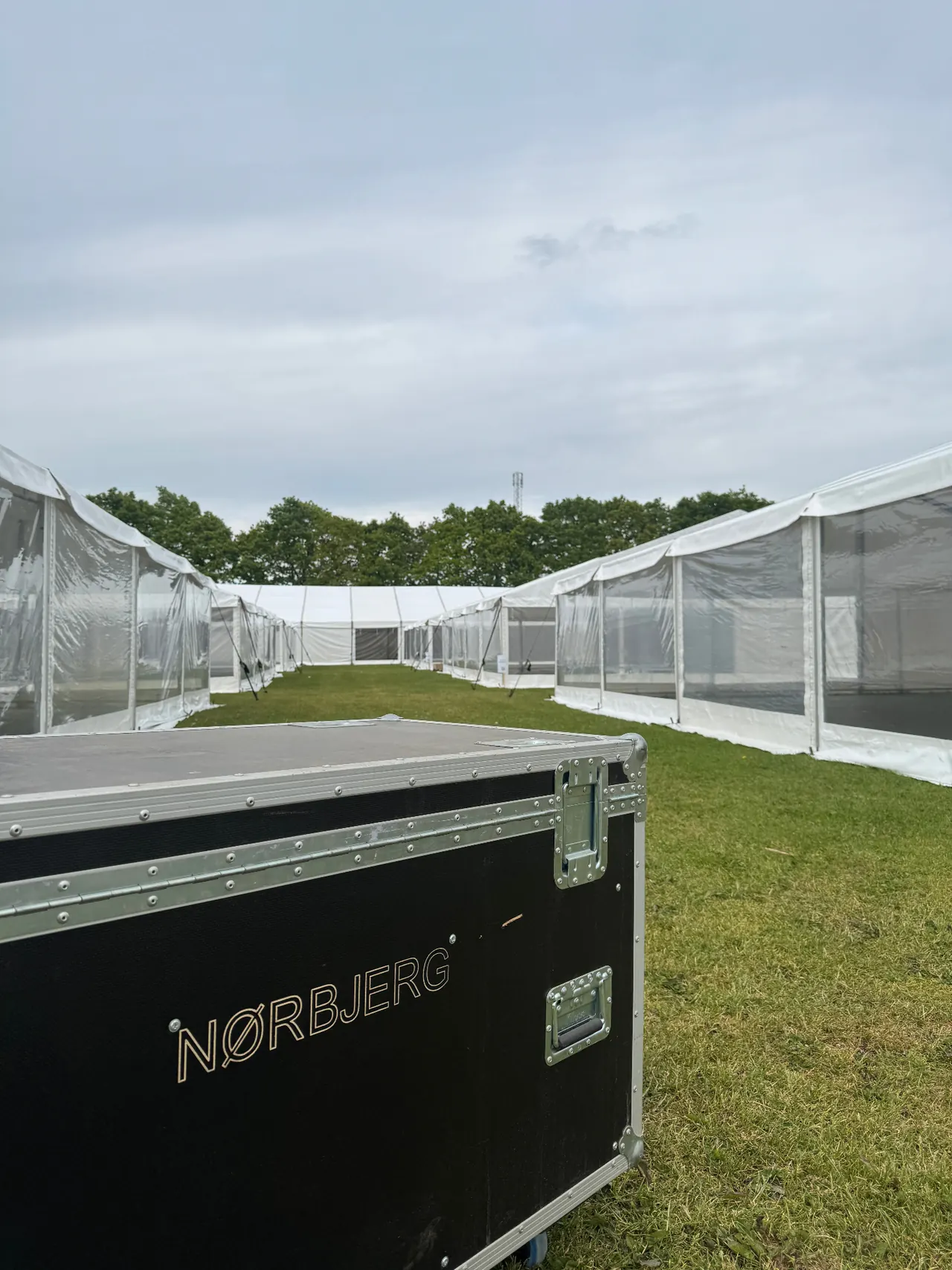 Flightcase i forgrunden og lange hvide eventtelte på en græsplæne