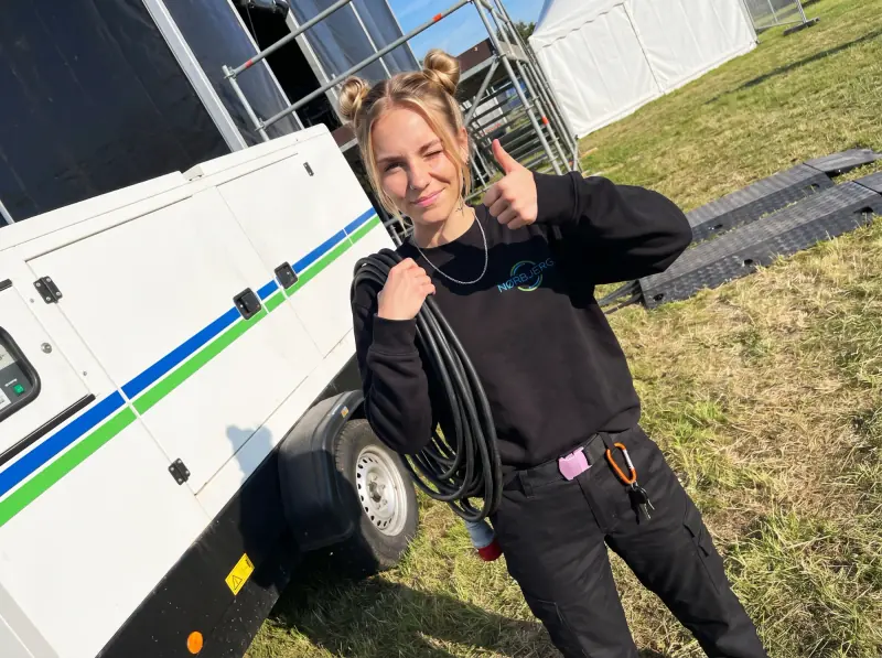 Nørbjerg El-medarbejder med strømkabel med rødt CEE-stik foran en hvid generator på trailer ved et event