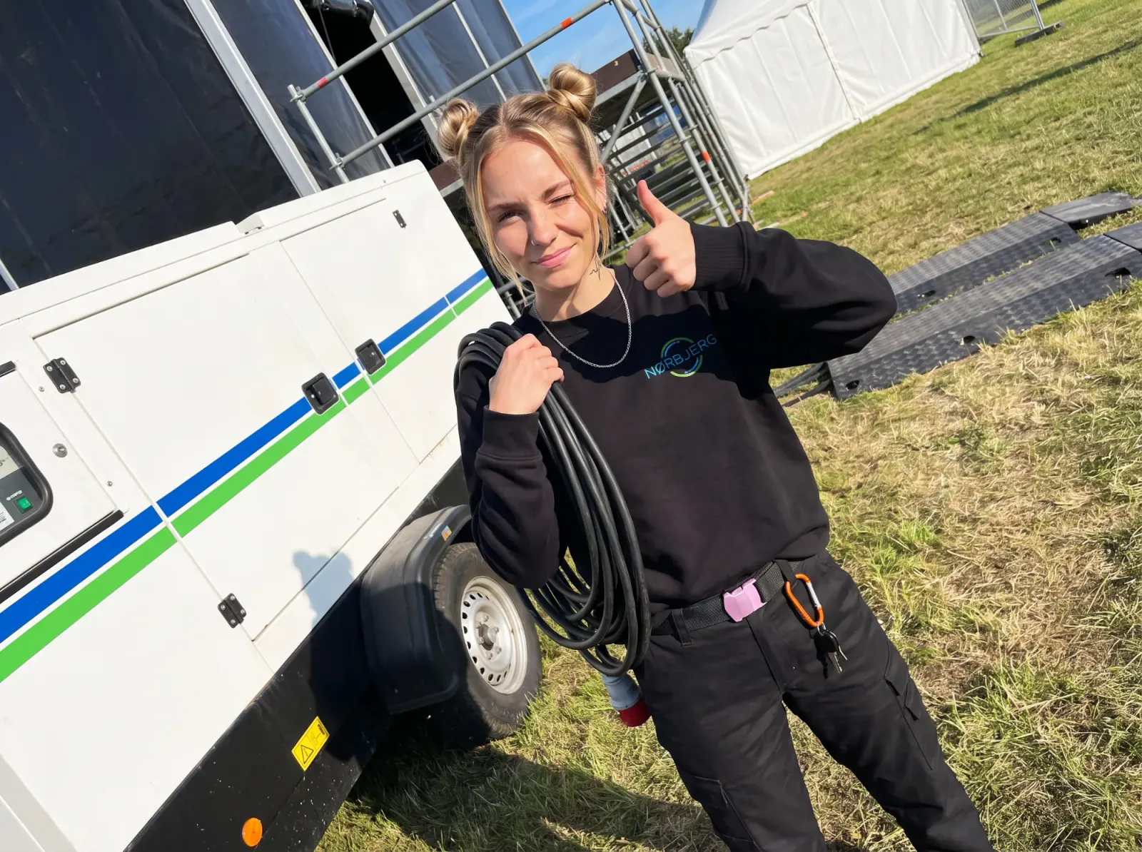 Nørbjerg El-medarbejder med strømkabel med rødt CEE-stik foran en hvid generator på trailer ved et event