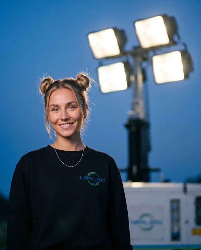 Nørbjerg El-medarbejder foran et lystårn med fire projektører i aftenlys